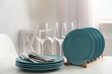 Photo of Set of clean dishes, cutlery and wineglasses on white table indoors