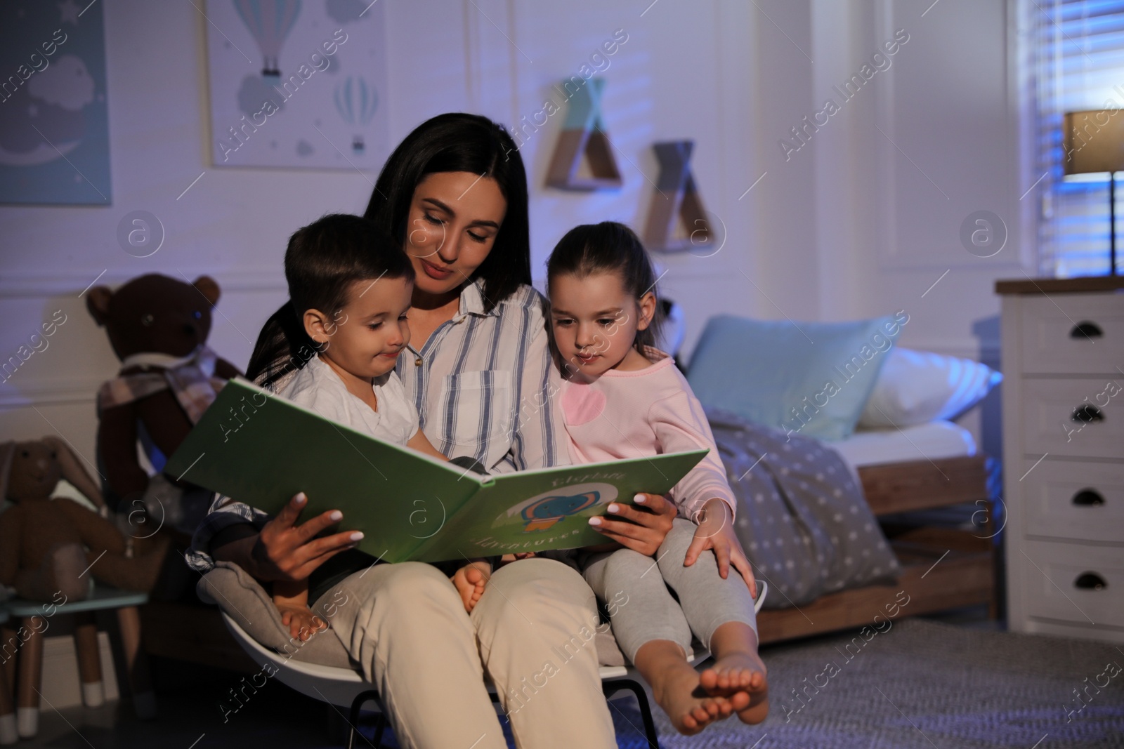 Photo of Mother reading bedtime story to her children at home