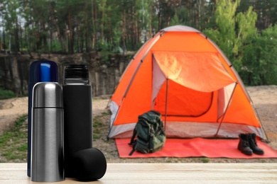 Image of Modern thermo bottles outdoors, space for text. Camping season 