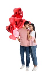 Photo of Happy young couple with heart shaped balloons isolated on white. Valentine's day celebration
