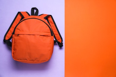 Stylish orange backpack on color background, top view. Space for text