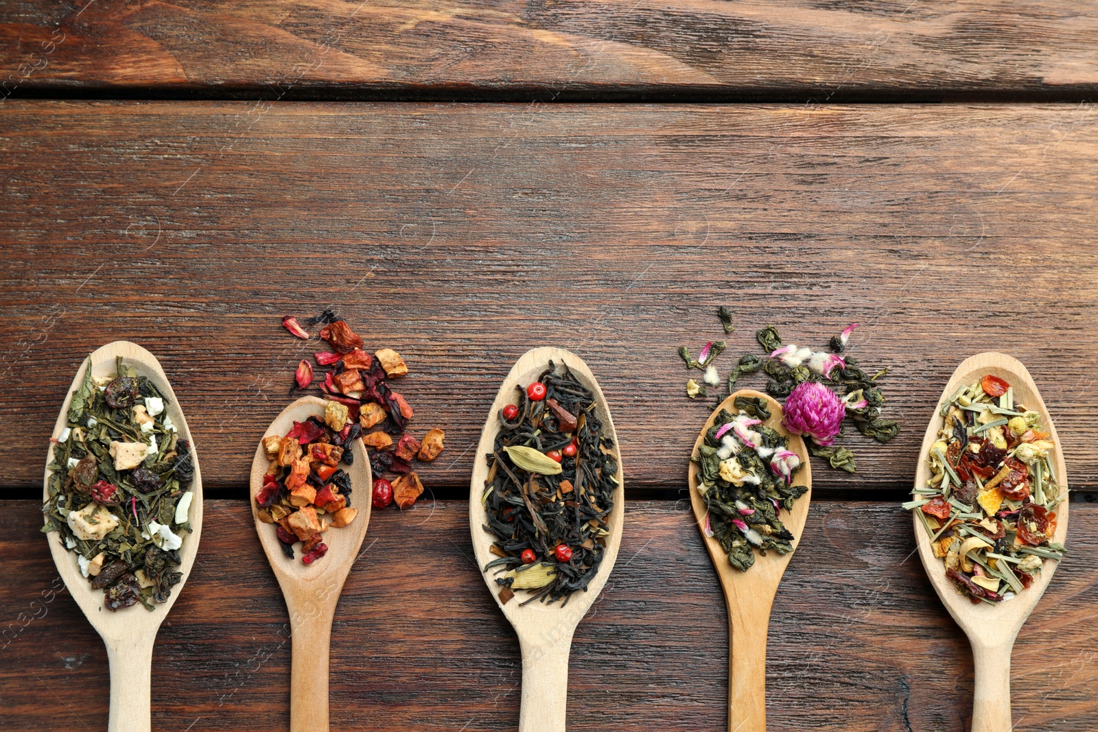 Photo of Flat composition with spoons of dried herbal tea leaves on wooden table. Space for text