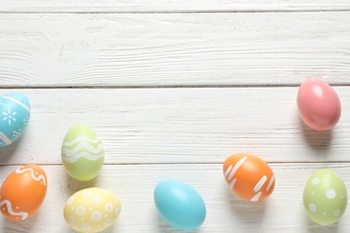 Photo of Flat lay composition of painted Easter eggs on wooden background, space for text