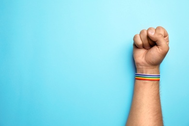 Man with rainbow ribbon on blue background, top view and space for text. Gay symbol