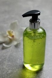 Photo of Dispenser of liquid soap on grey table