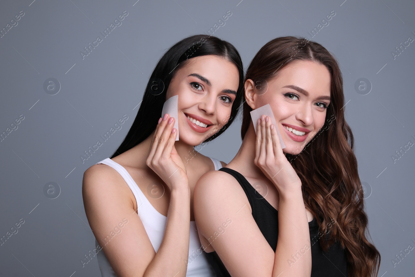 Photo of Beautiful women using mattifying wipes on grey background