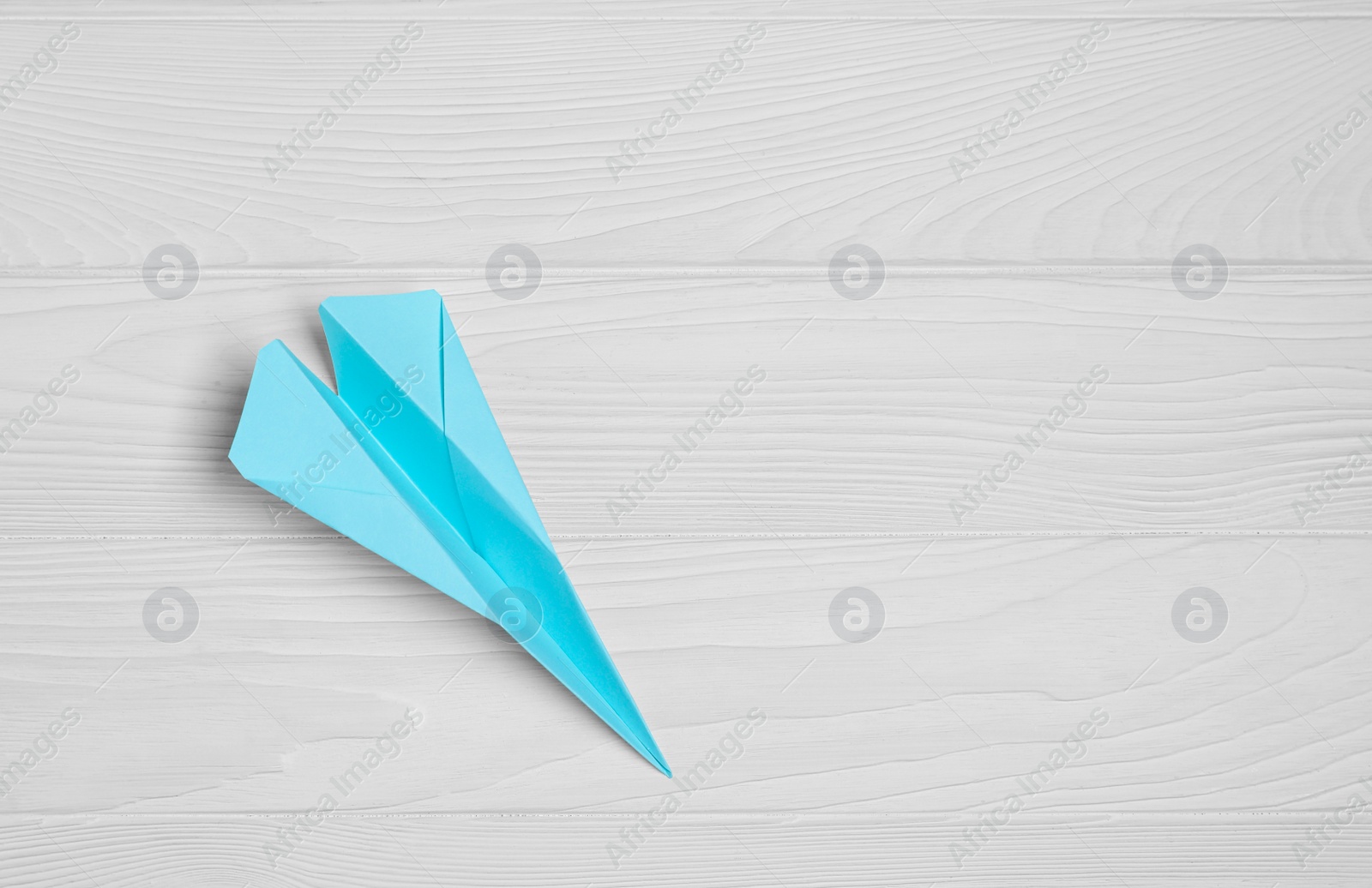 Photo of Handmade paper plane on white wooden table, top view. Space for text
