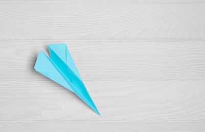 Photo of Handmade paper plane on white wooden table, top view. Space for text