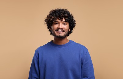Photo of Handsome young smiling man on beige background, space for text