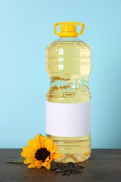 Photo of Bottle of cooking oil, sunflower and seeds on wooden table