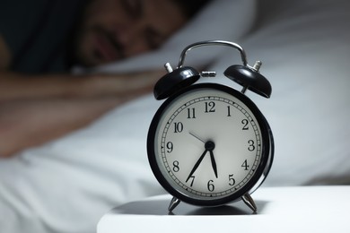 Photo of Man sleeping in bed, focus on alarm clock. Space for text