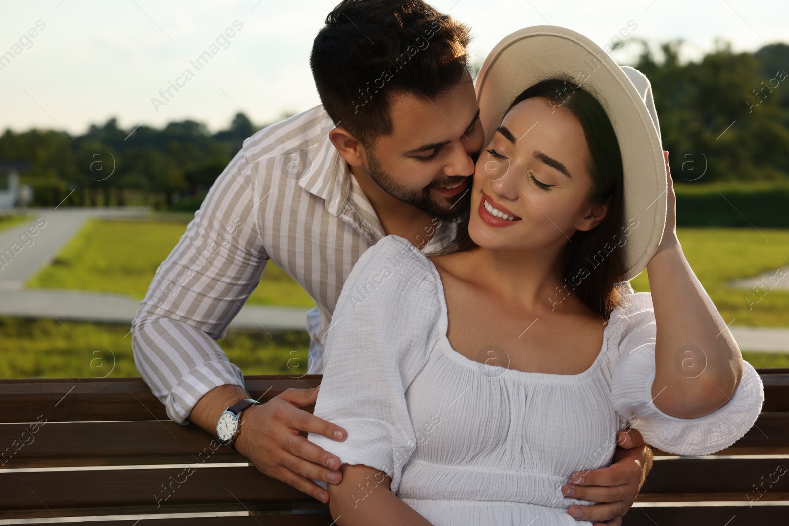 Photo of Romantic date. Beautiful couple spending time together on bench outdoors