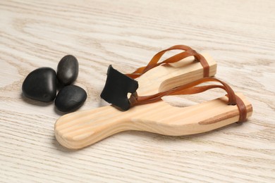 Slingshot with stones on wooden table, closeup