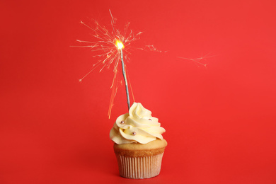Photo of Birthday cupcake with sparkler on red background