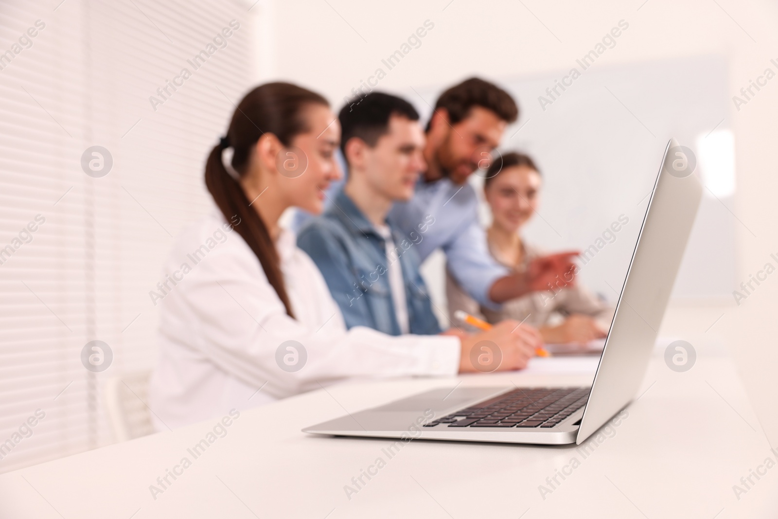 Photo of Teacher giving lesson in driving school, focus on laptop on white desk