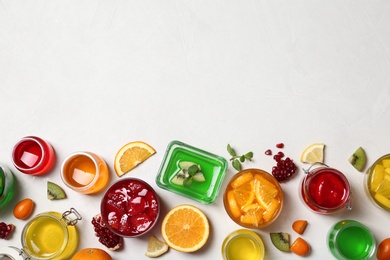 Flat lay composition with different jelly desserts on light background, space for text