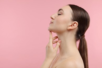 Photo of Beautiful woman touching her chin on pink background. Space for text