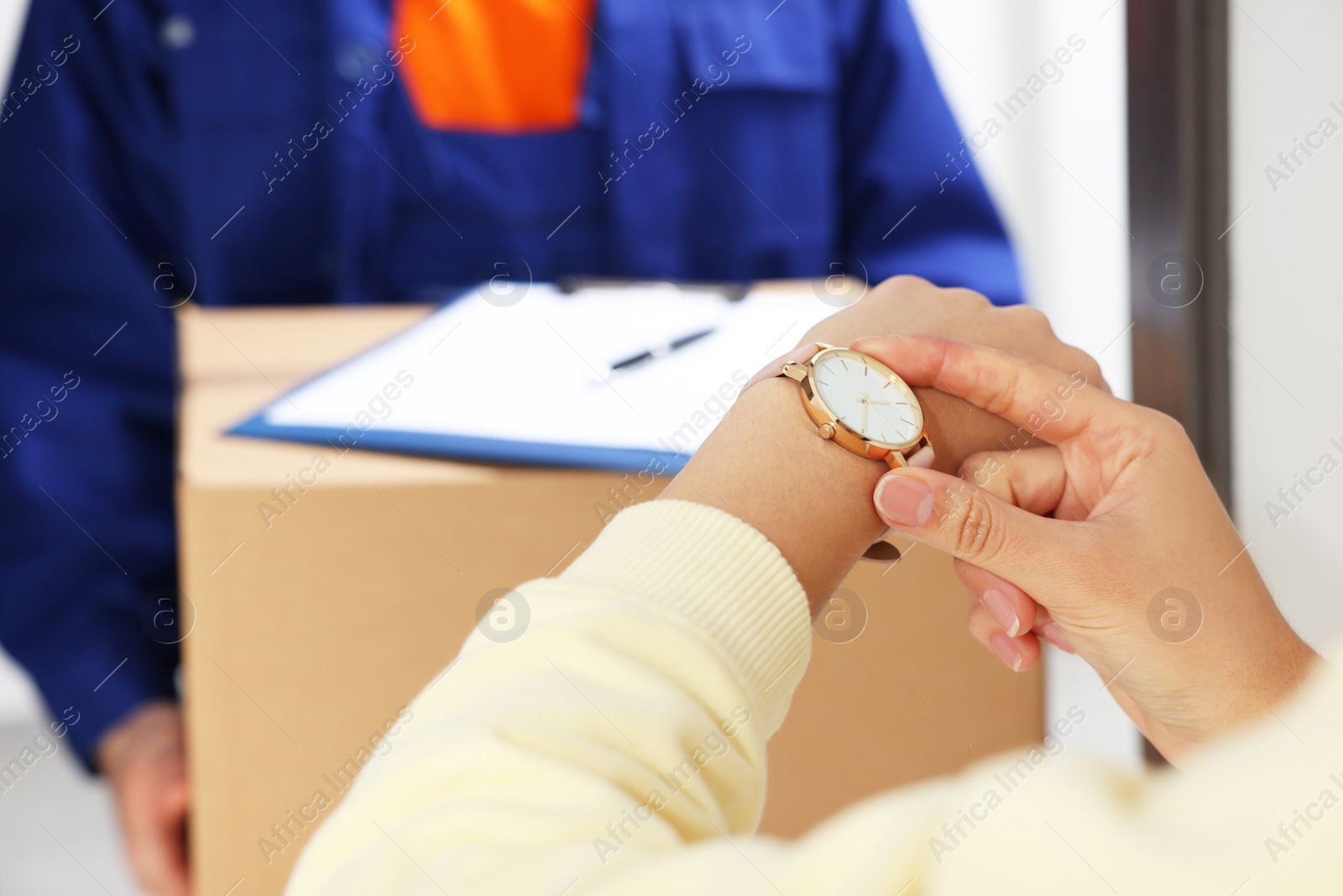 Photo of Closeup view of woman checking time near courier with parcel