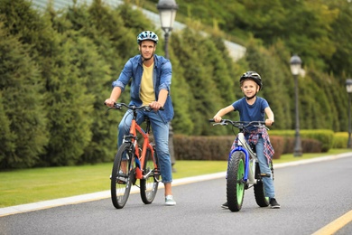 Dad and son riding modern bicycles outdoors