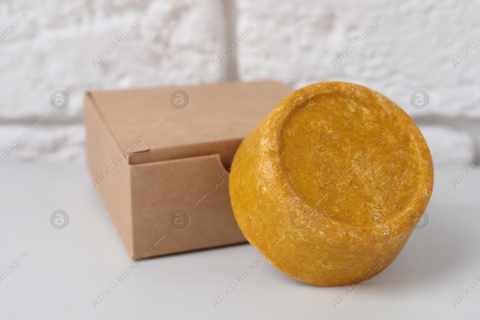 Photo of Orange solid shampoo bar and box on white table, closeup