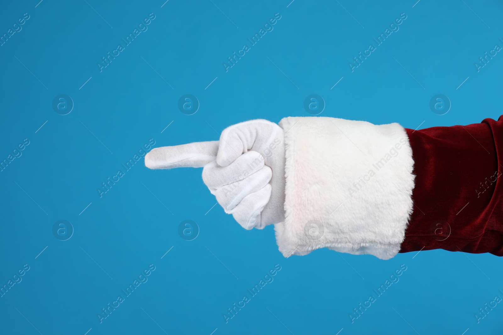 Photo of Santa Claus pointing at something on blue background, closeup of hand