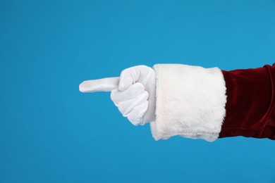 Photo of Santa Claus pointing at something on blue background, closeuphand