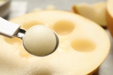 Scoop with melon ball on blurred background, closeup. Space for text