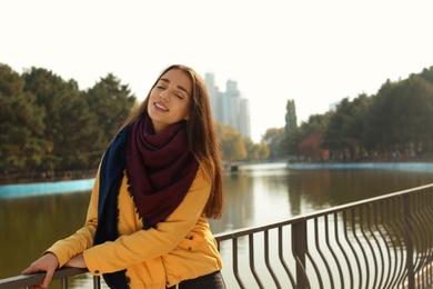 Photo of Young beautiful woman near pond in park. Autumn walk