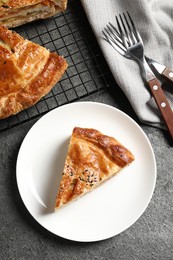 Photo of Piece of tasty homemade pie with filling served on grey table, flat lay