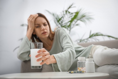 Photo of Woman taking medicine for hangover at home, focus on hand