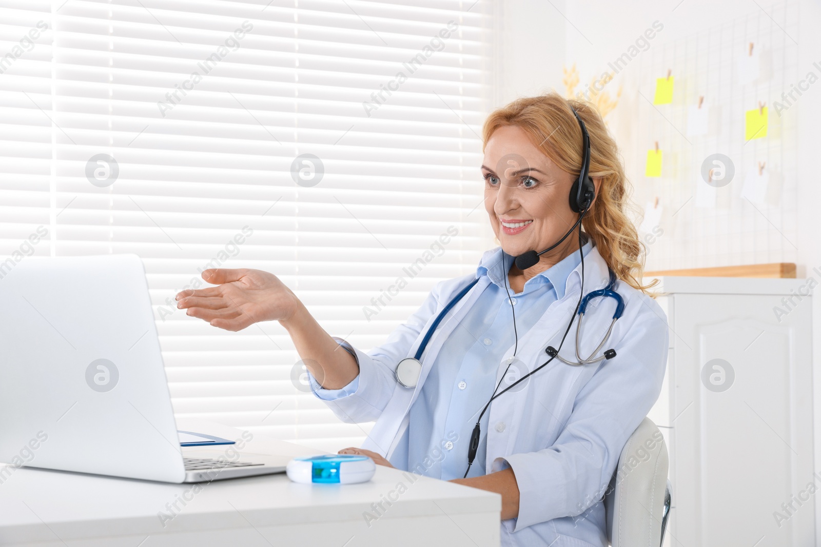 Photo of Doctor with laptop and headphones consulting patient in clinic. Online medicine concept