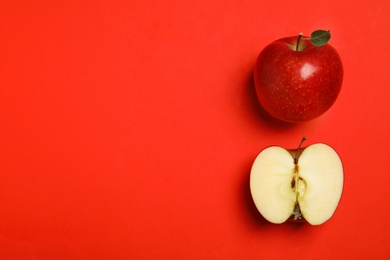 Flat lay composition with ripe juicy apples on red background, space for text