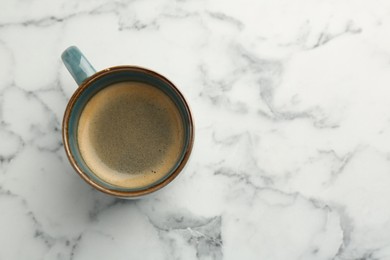 Photo of Tasty coffee in cup on white marble table, top view. Space for text