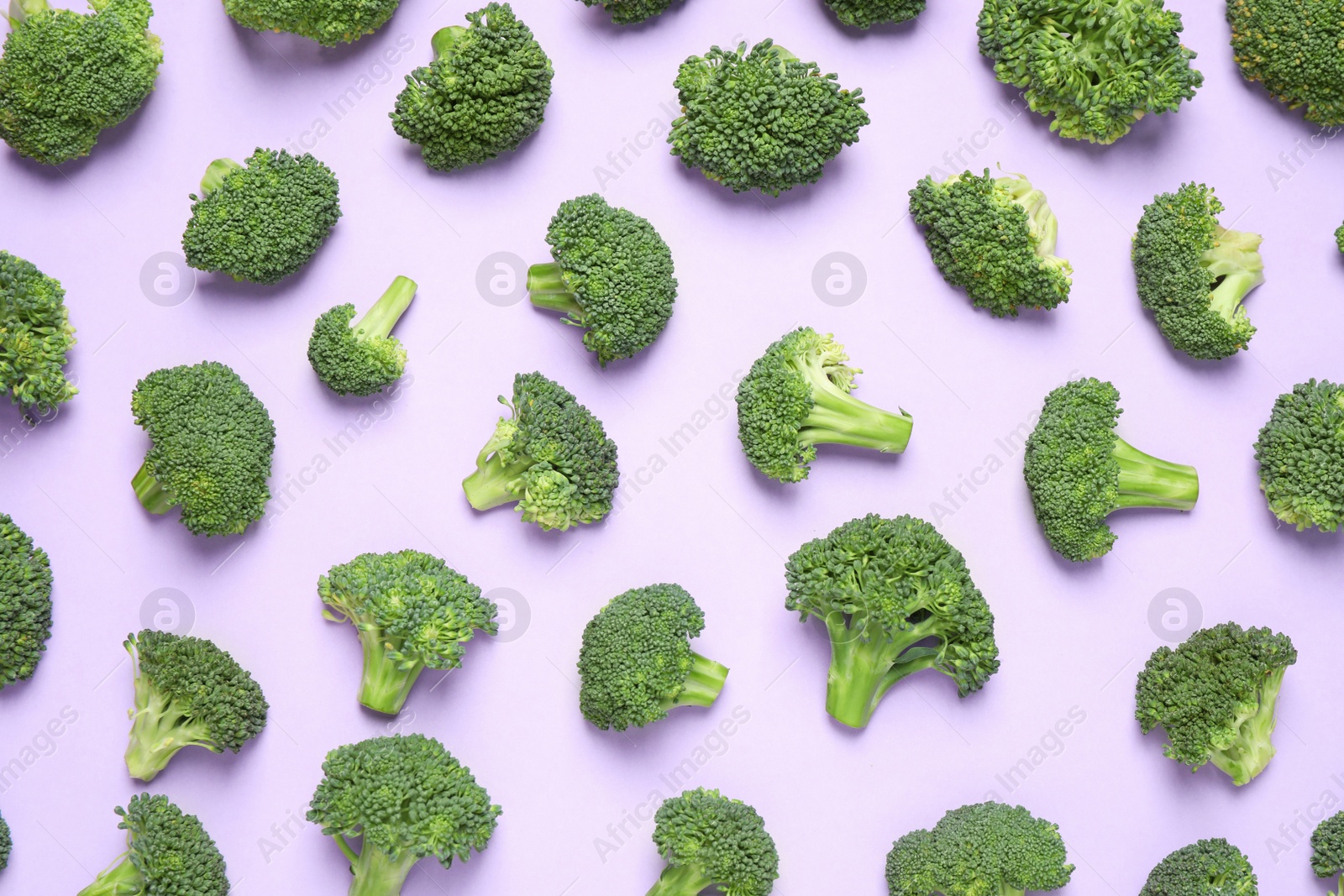 Photo of Fresh tasty broccoli on violet background, flat lay