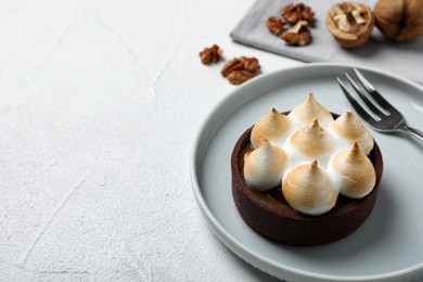 Photo of Delicious salted caramel chocolate tart with meringue served on light table, space for text