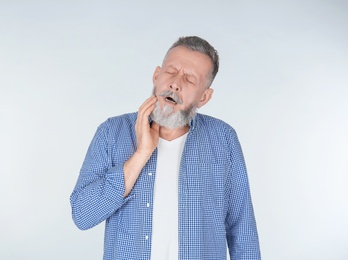 Man suffering from toothache on light background