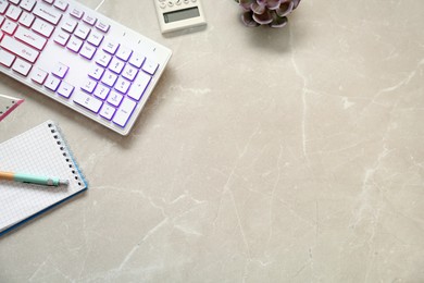 Photo of Modern RGB keyboard and stationery on light marble table, flat lay. Space for text