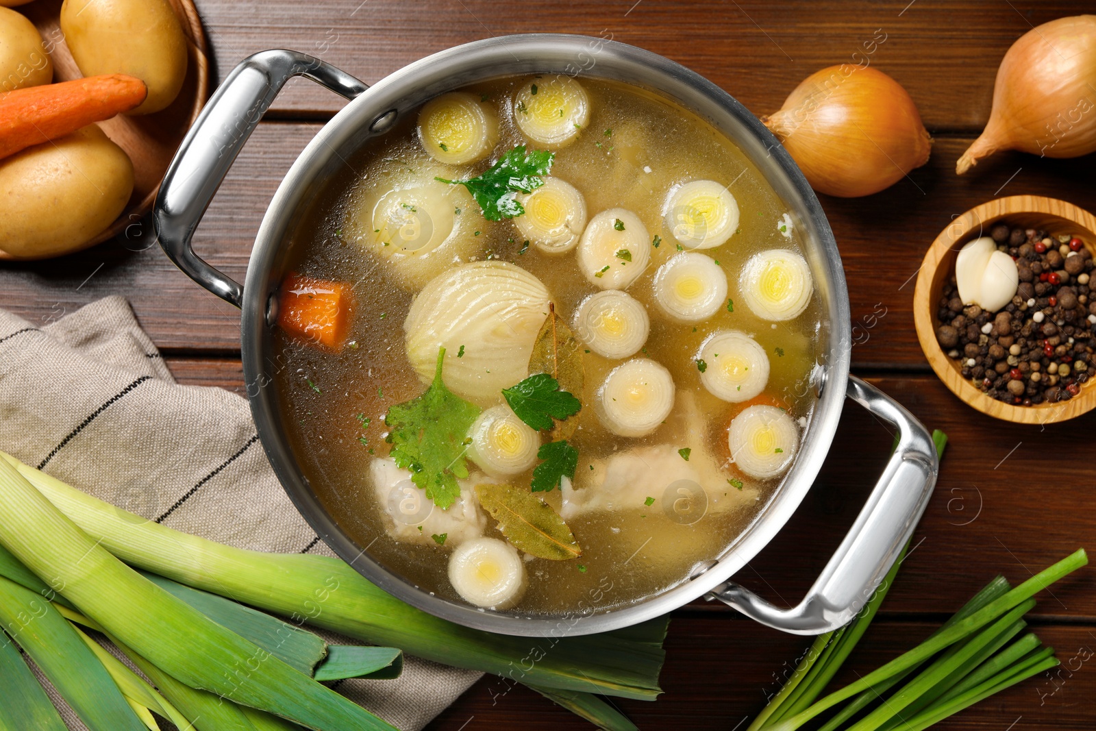 Photo of Pot with tasty bouillon and different ingredients on wooden table, flat lay