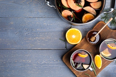 Photo of Tasty mulled wine with spices on grey wooden table, flat lay. Space for text