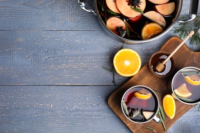 Tasty mulled wine with spices on grey wooden table, flat lay. Space for text