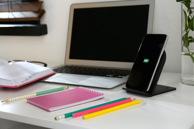 Photo of Modern workplace and smartphone charging with wireless pad