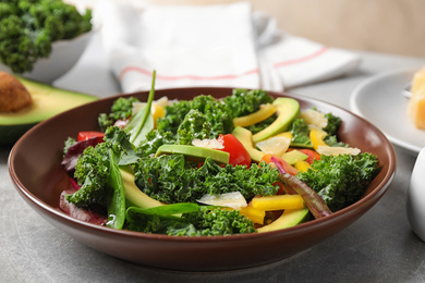 Photo of Tasty fresh kale salad on light grey table, closeup