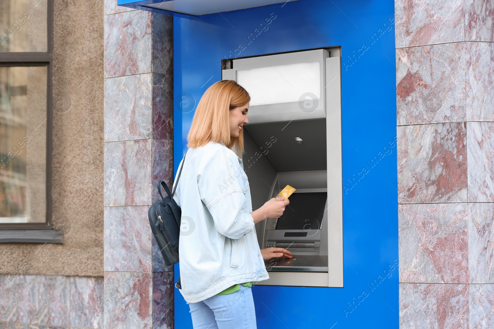 Photo of Beautiful woman using cash machine for money withdrawal outdoors