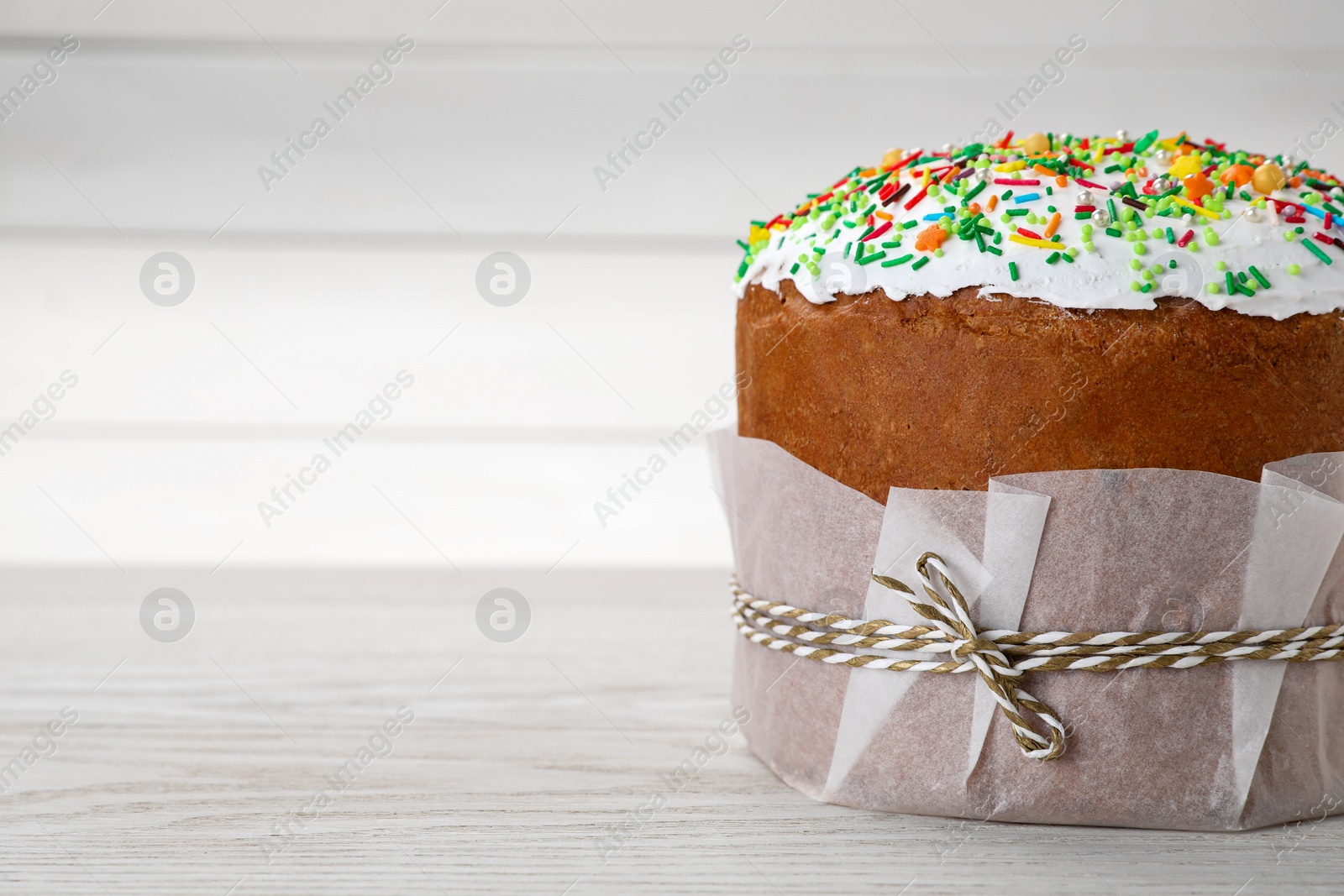 Photo of Traditional Easter cake with sprinkles on white wooden table, closeup. Space for text