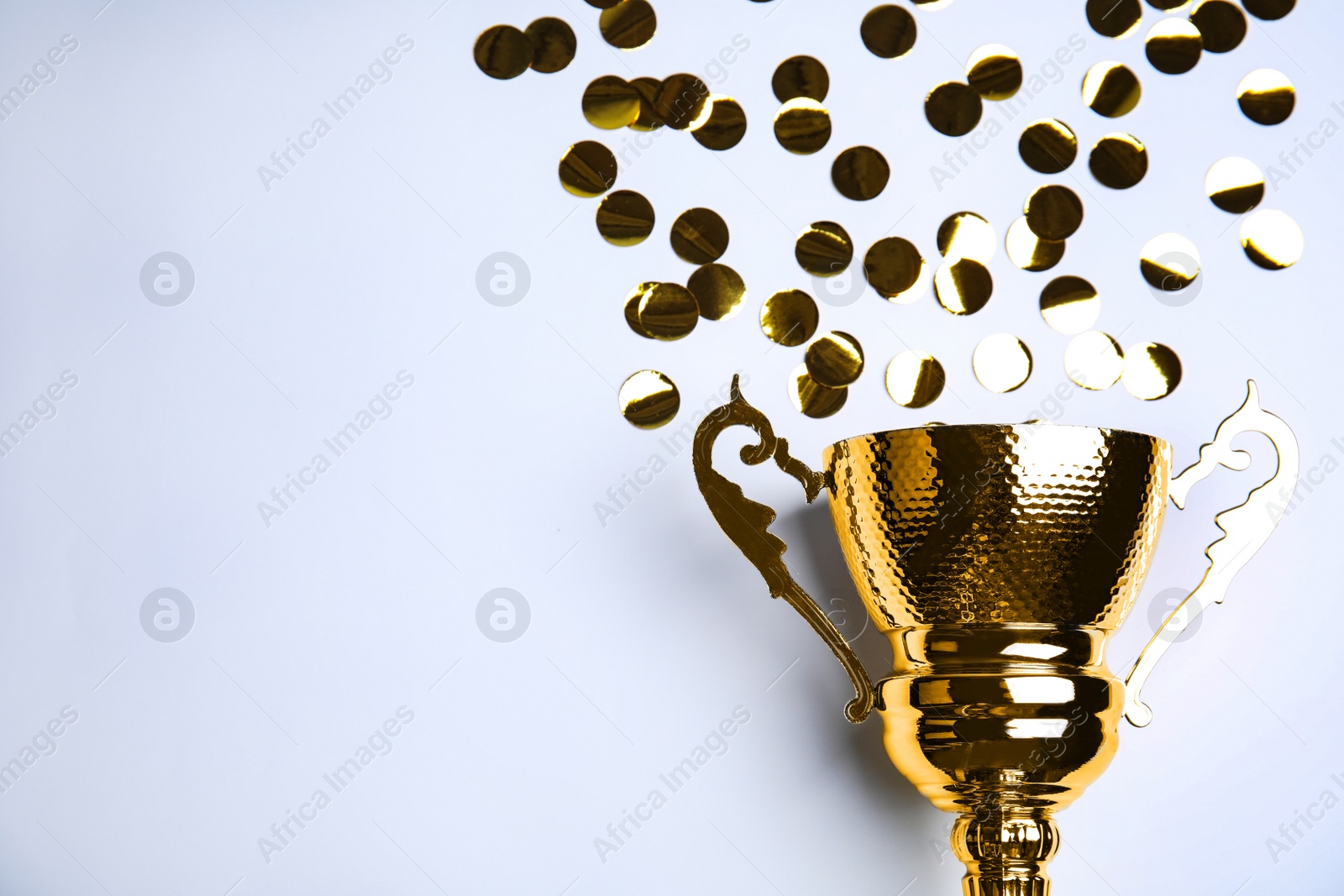 Photo of Gold trophy cup and confetti on white background, top view