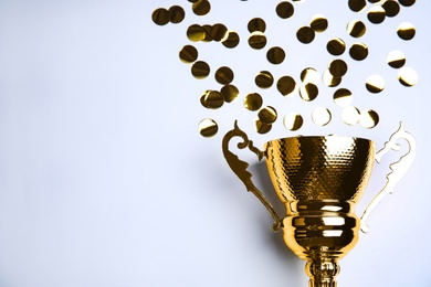 Gold trophy cup and confetti on white background, top view