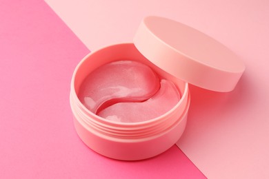 Photo of Jar of under eye patches on pink background, closeup. Cosmetic product