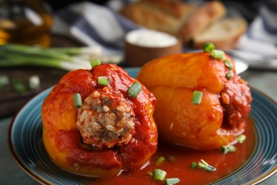Photo of Delicious stuffed peppers served with green onion on blue plate, closeup