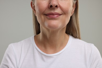 Photo of Mature woman with healthy skin on grey background, closeup