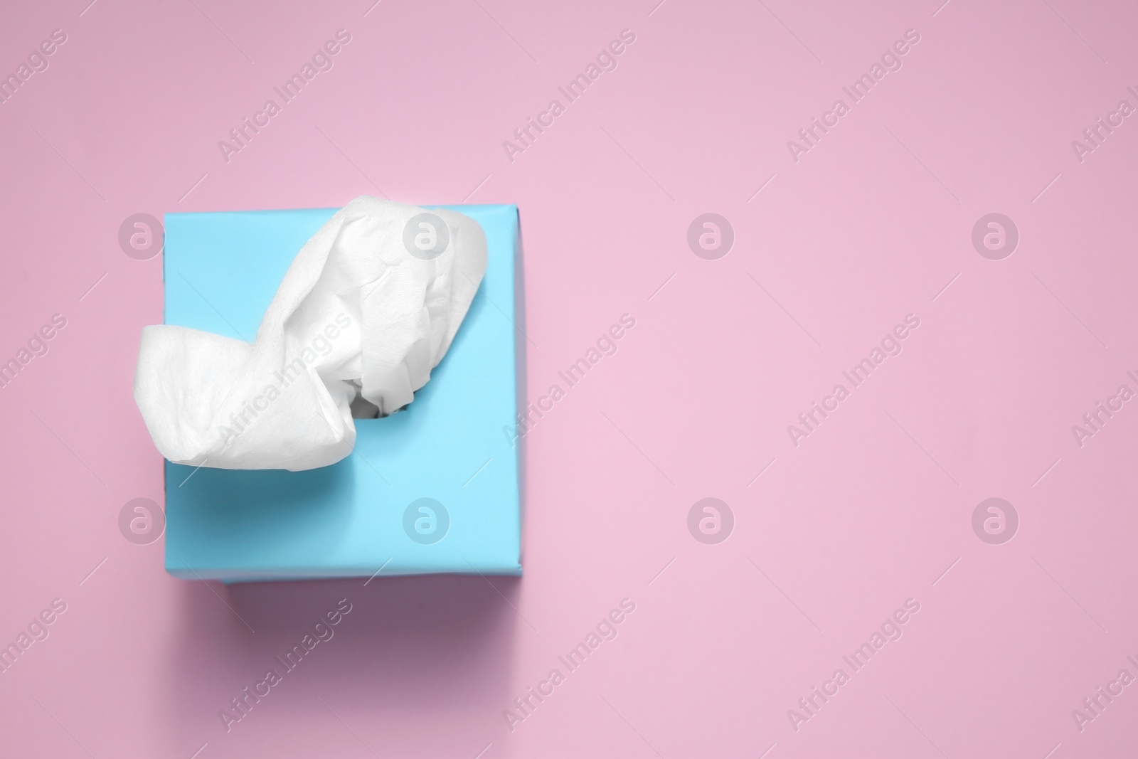 Photo of Box with paper tissues on pink background, top view. Space for text